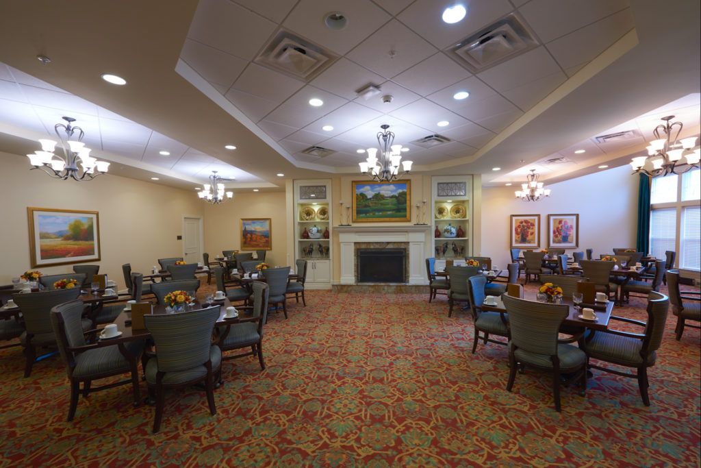 Elegant dining room with multiple tables and chairs, featuring a fireplace and chandeliers.