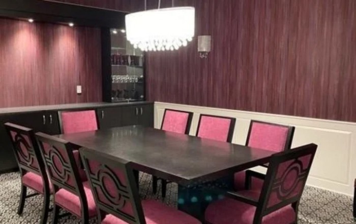 A modern dining room with a dark wooden table, upholstered chairs, and a stylish chandelier.