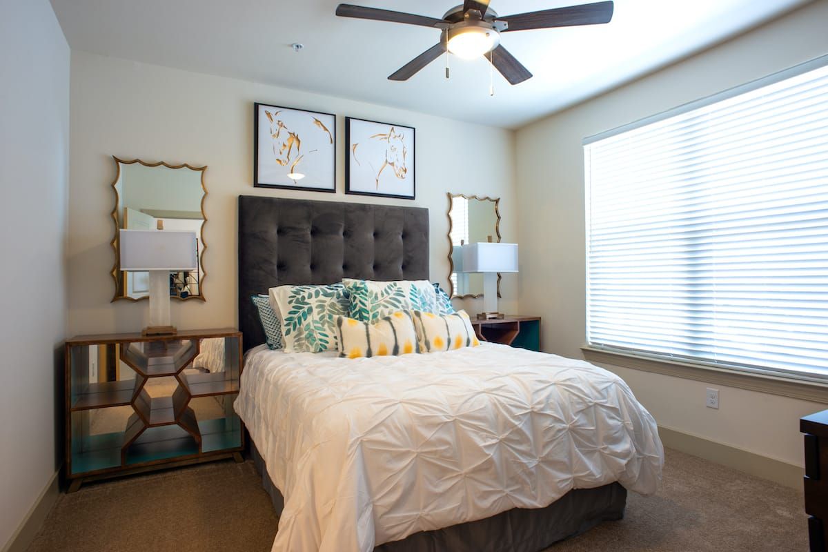A cozy and well-decorated bedroom featuring a plush bed, stylish pillows, matching mirrors, and artwork above the headboard.