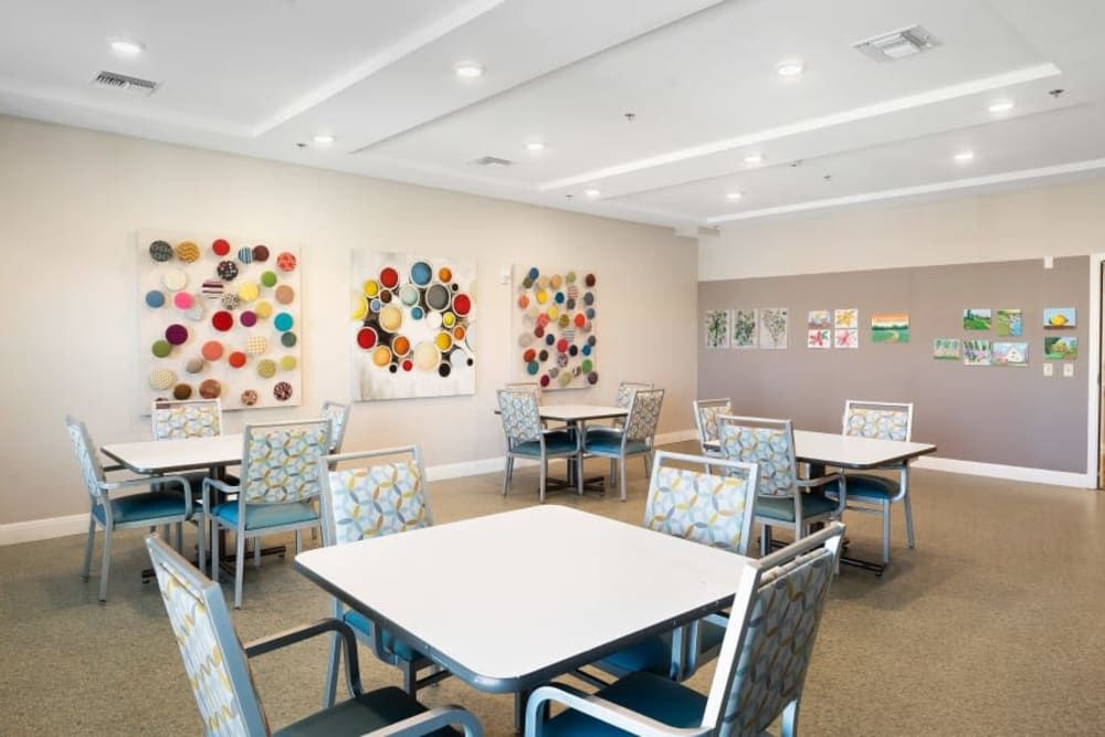 A modern room with colorful artworks on the walls and neatly arranged tables and chairs.