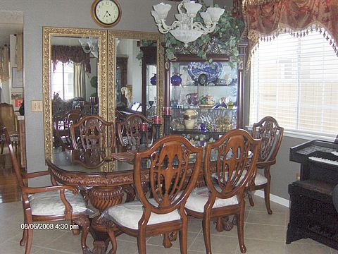 A classic dining room with ornate wooden furniture and a large mirror reflecting the space.
