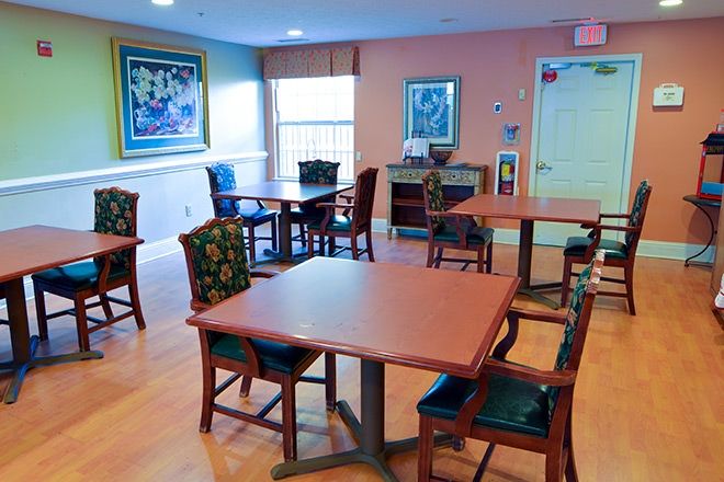 A cozy dining area with tables, chairs, and artwork on the walls.