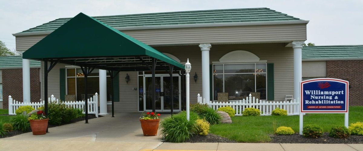 The entrance of a building featuring a green awning, columns, and landscaped surroundings.