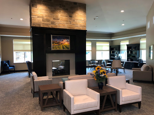 A stylish and modern lobby featuring a cozy seating area with white chairs, a stone fireplace, and vibrant floral arrangements.