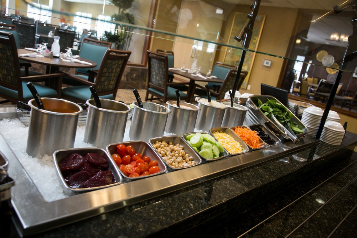 A well-stocked salad bar at a restaurant with various fresh vegetables and toppings.