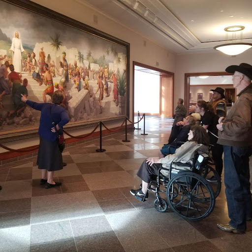 A guided tour at a museum, with visitors engaging with a large mural.