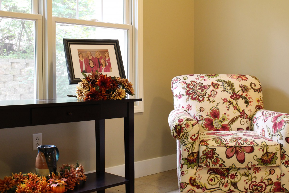 A cozy living room corner with a floral couch and autumn-themed decorations.