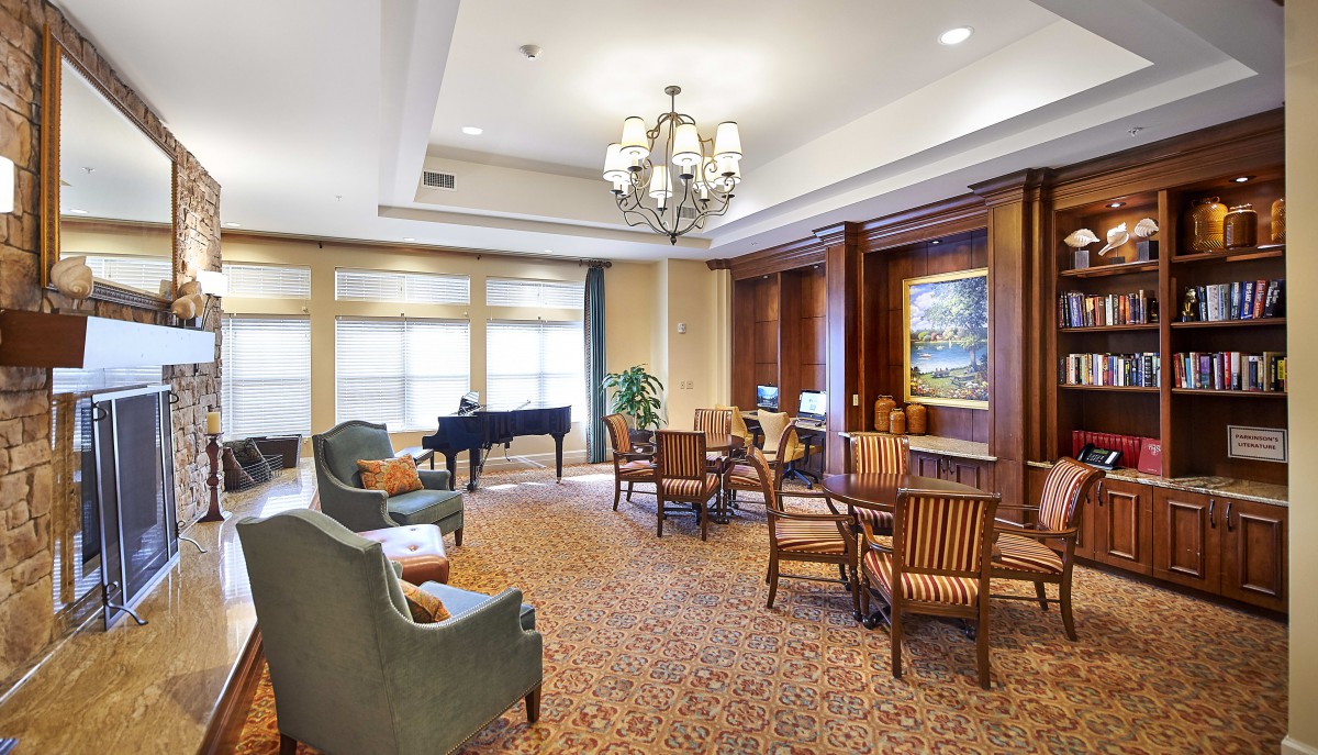 A spacious and elegantly furnished living area with a grand piano, comfortable seating, and a chandelier.