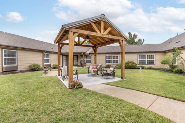 A cozy outdoor patio with a wooden pergola and seating area in a spacious yard.