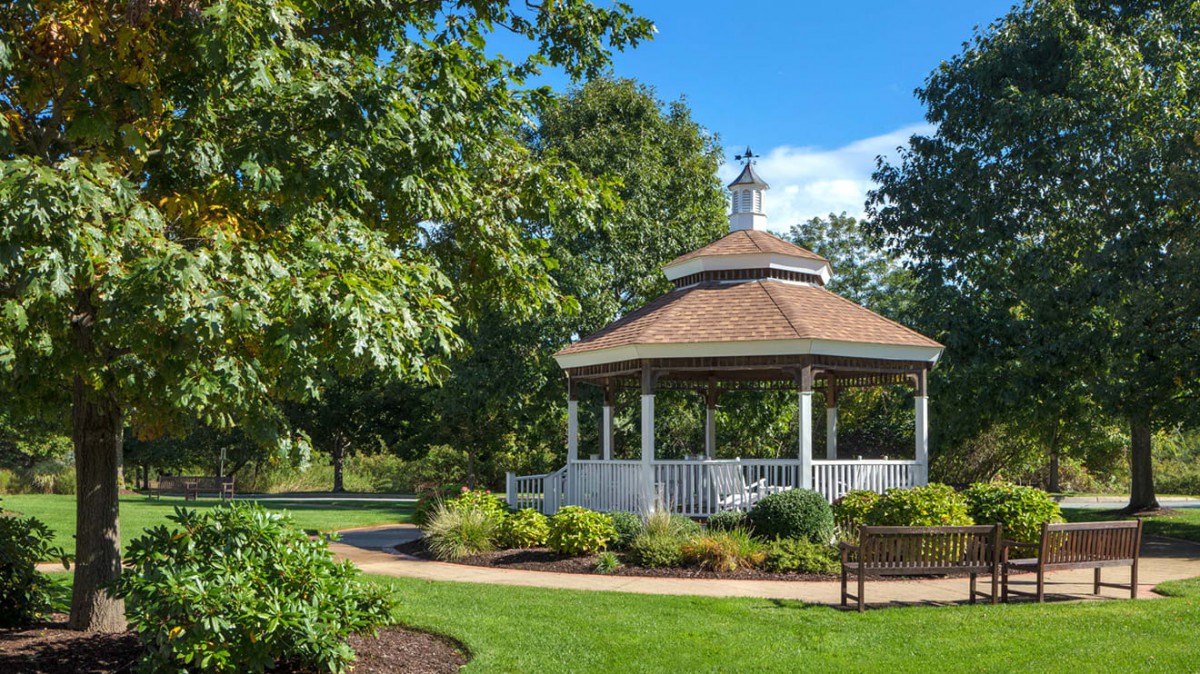 A picturesque gazebo surrounded by lush greenery in a serene park setting.