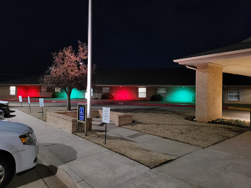 A view of a building illuminated with festive red and green lights at night.