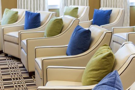 A row of stylish chairs adorned with blue and green pillows in a well-furnished interior space.