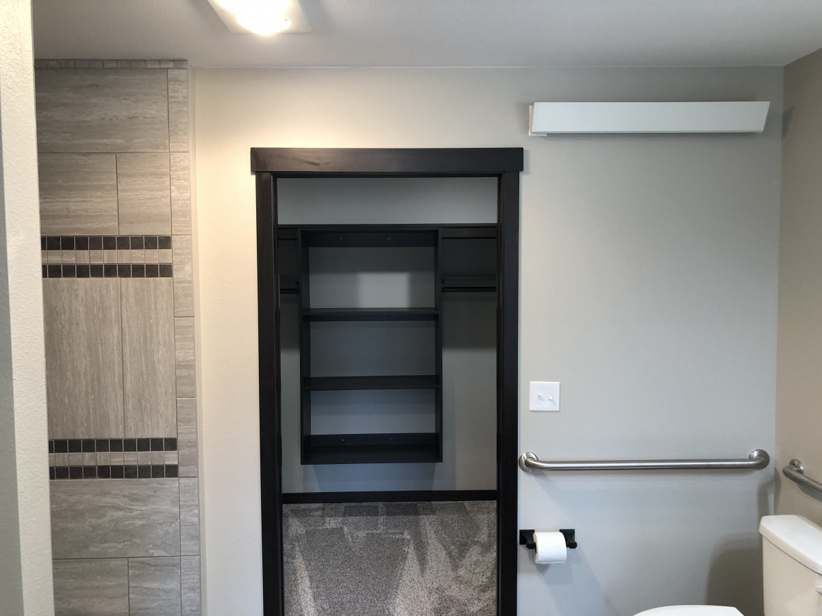 A modern bathroom with built-in shelving and tiled walls.