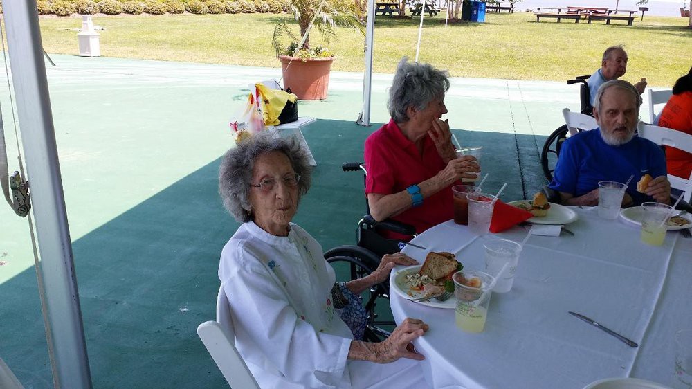 Elderly individuals enjoying a meal together outdoors.