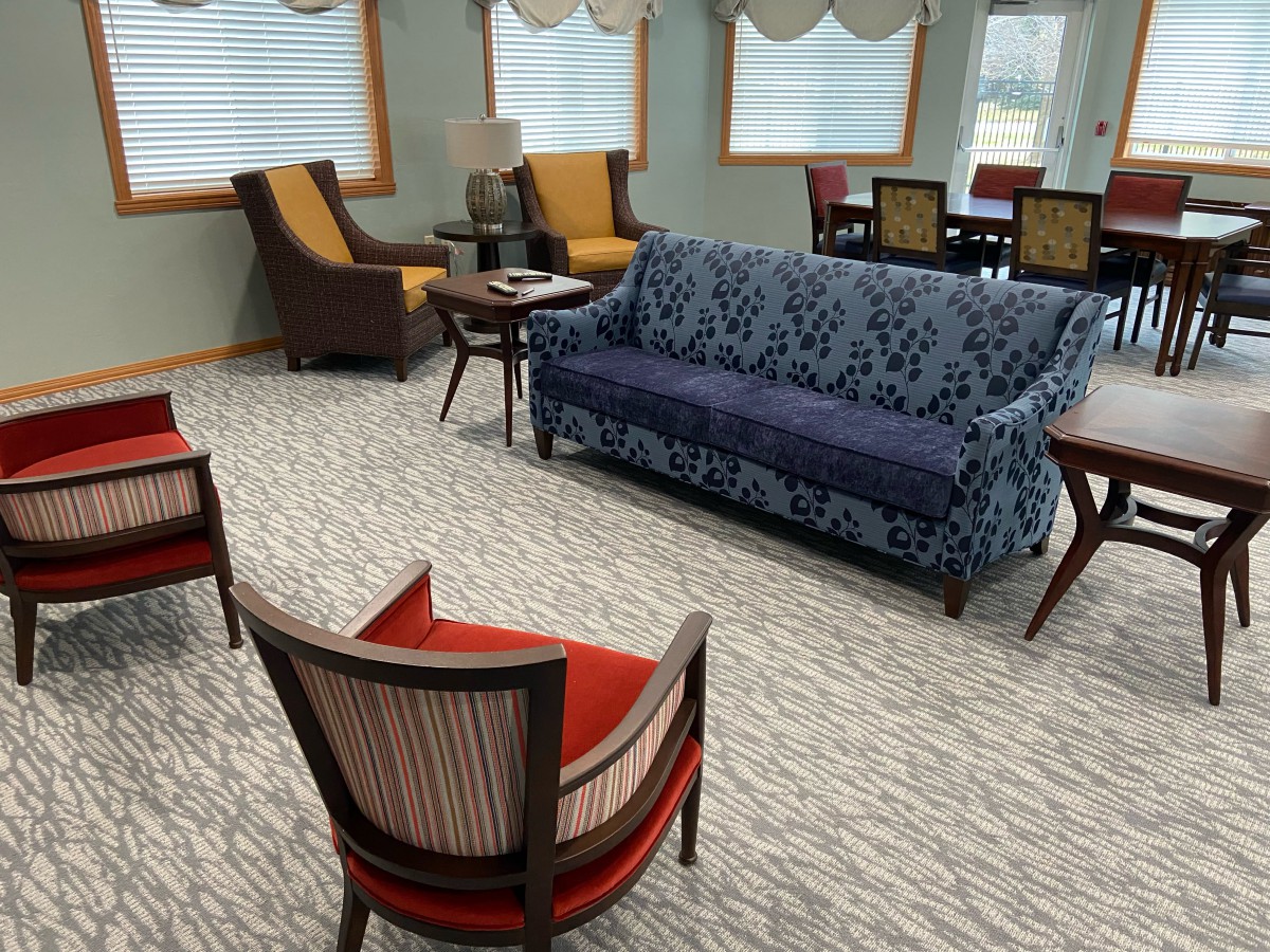 A cozy living room with a variety of seating options including a patterned sofa and several chairs.