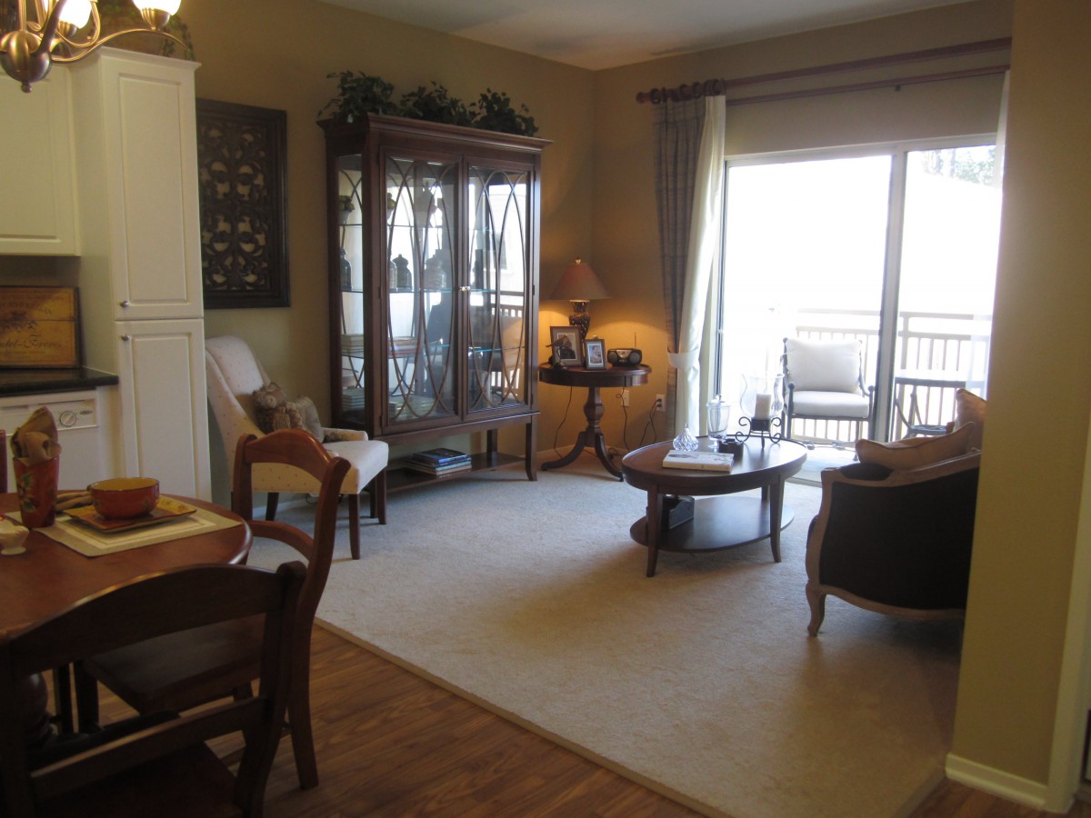 A cozy living room with a carpet, furniture, and large windows.