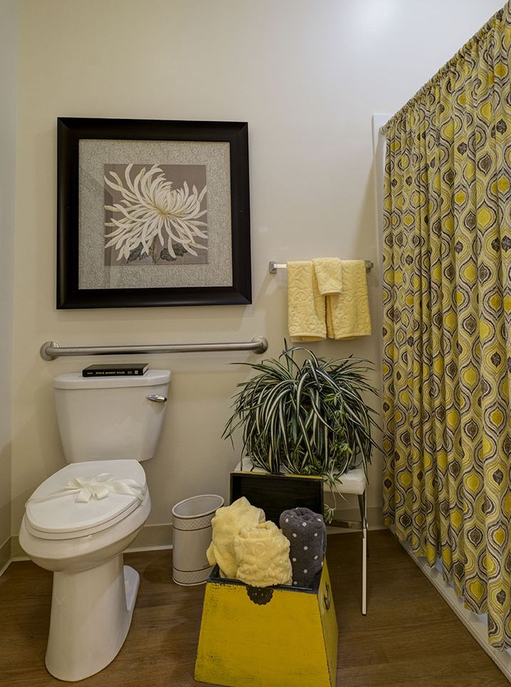 A neatly decorated bathroom with a focus on yellow accents and stylish wall art.