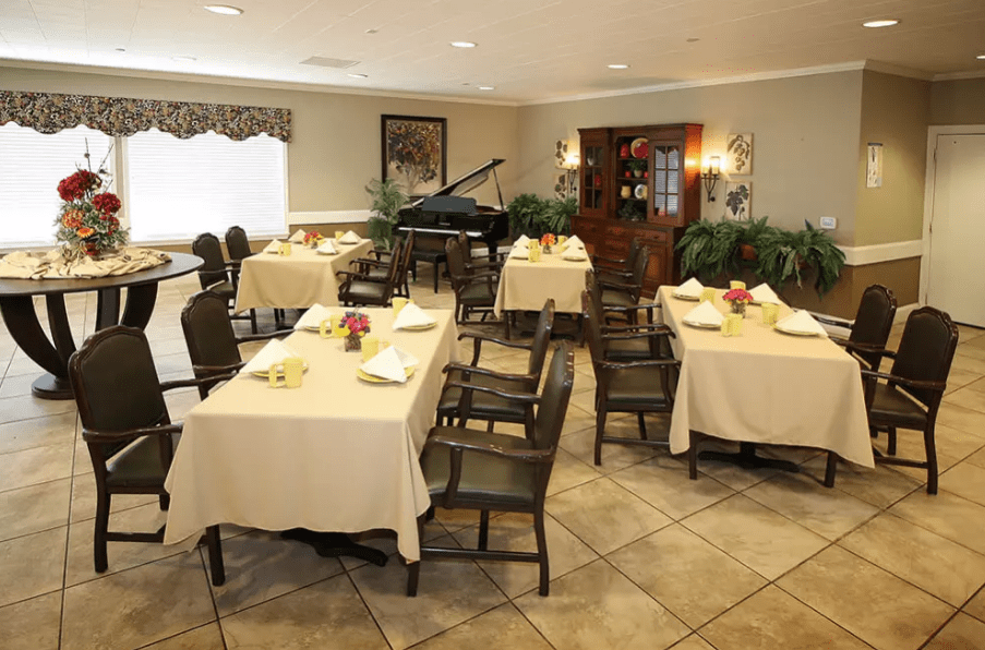 An elegantly decorated dining area with several tables and a piano in the corner.
