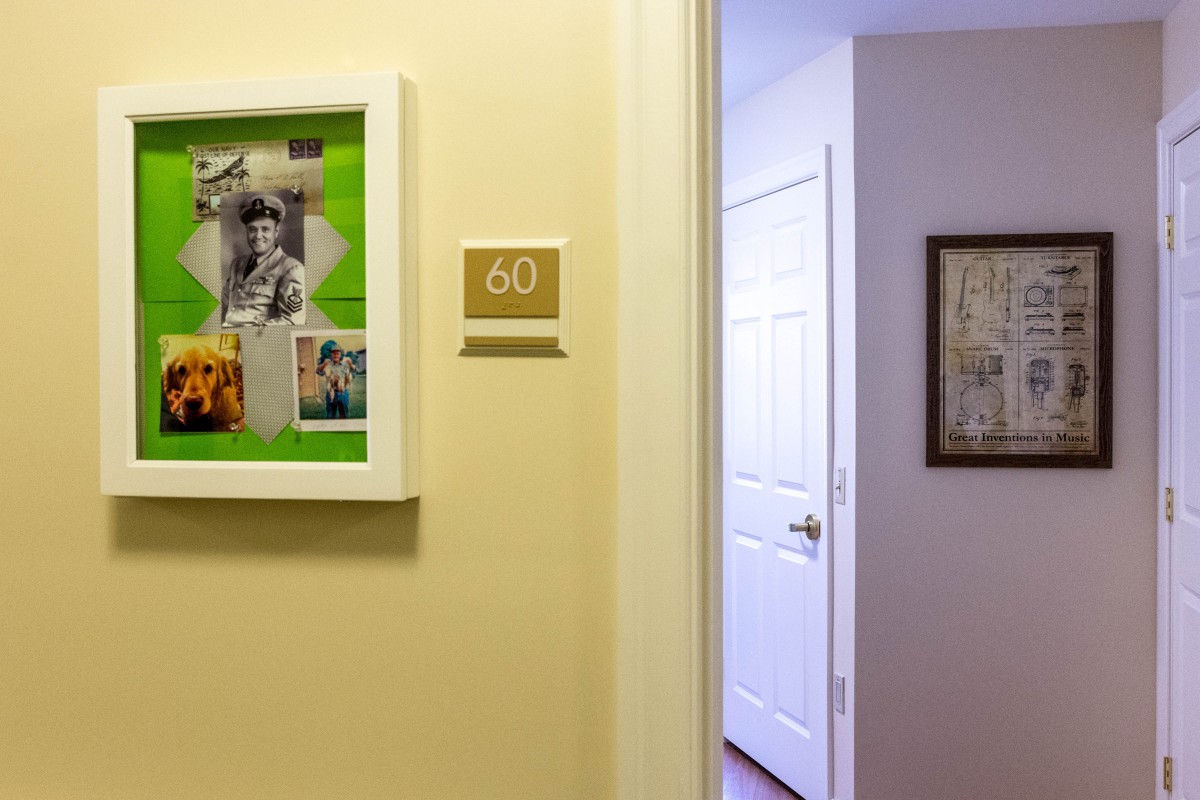 A hallway with a doorway leading to a room, featuring a framed picture and a room number '30' on the wall.