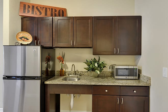 A modern kitchen with dark wood cabinets, a refrigerator, and a microwave on the countertop.