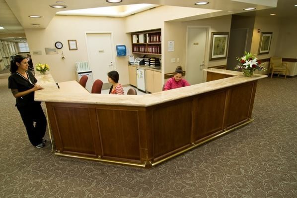 A reception area with a curved desk and two employees working behind it.