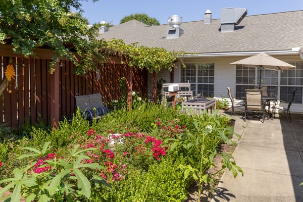 A cozy backyard garden with vibrant flowers, lush plants, and a patio area for relaxation.