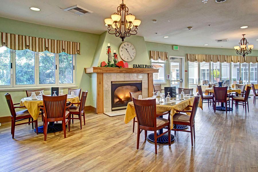 A cozy dining area with a fireplace, tables, and chairs arranged under warm lighting.