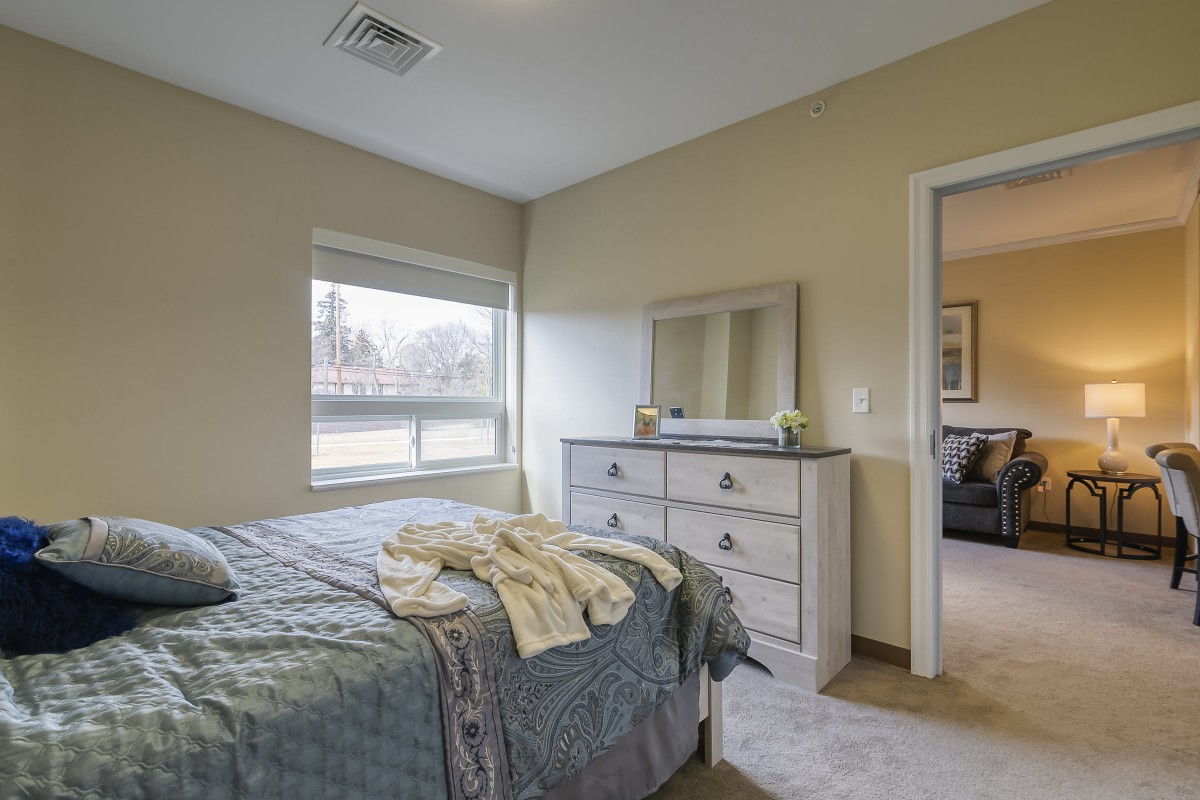 A cozy bedroom with a bed, dresser, and mirror.