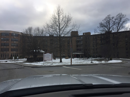 A view of a residential building on a snowy day, with bare trees and a cloudy sky.