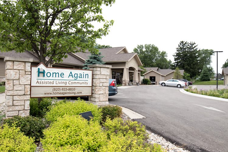 Entrance to an assisted living community with a sign that reads 'Home Again'.