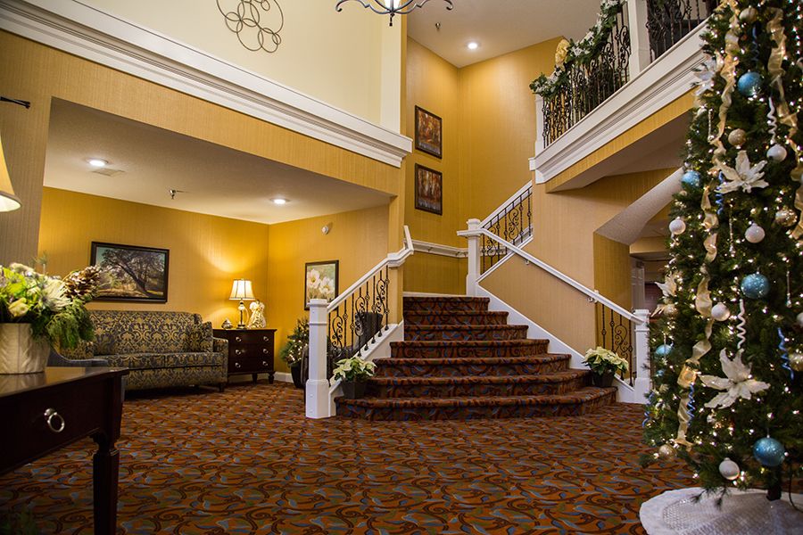 A warmly lit lobby with a staircase and elegant furnishings.