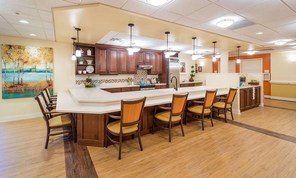 A modern kitchen featuring a spacious counter with wooden chairs and pendant lighting.
