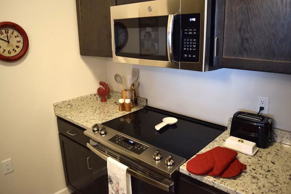 A modern kitchen with a stove, microwave, and stylish countertop.