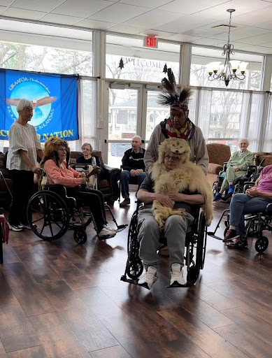 Residents of a care home enjoy a lively community event featuring cultural performances and interactions.