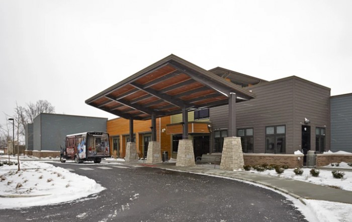 A modern building entrance with a large canopy and snow-covered surroundings.