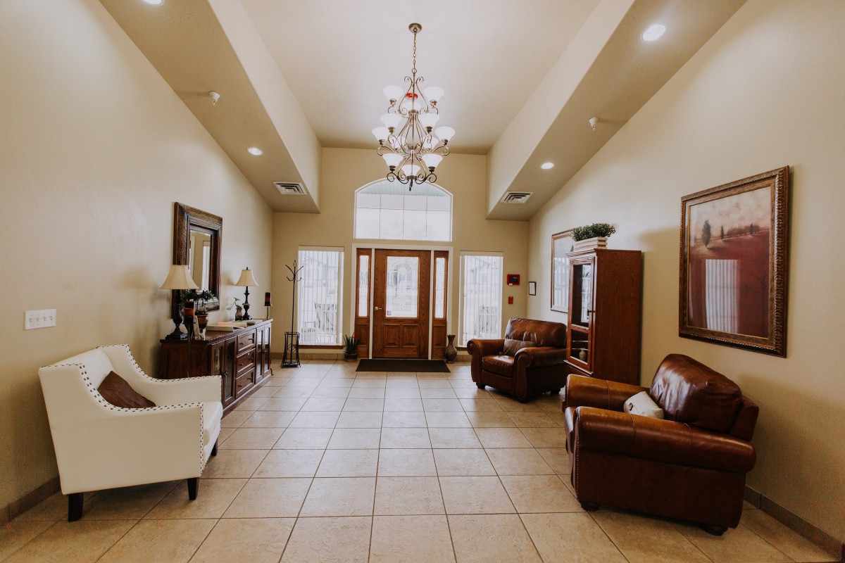 A spacious and elegantly designed living room featuring a chandelier, tiled flooring, and comfortable seating.