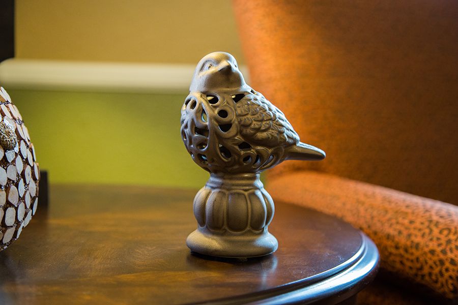 A decorative ceramic bird figurine placed on a wooden table.