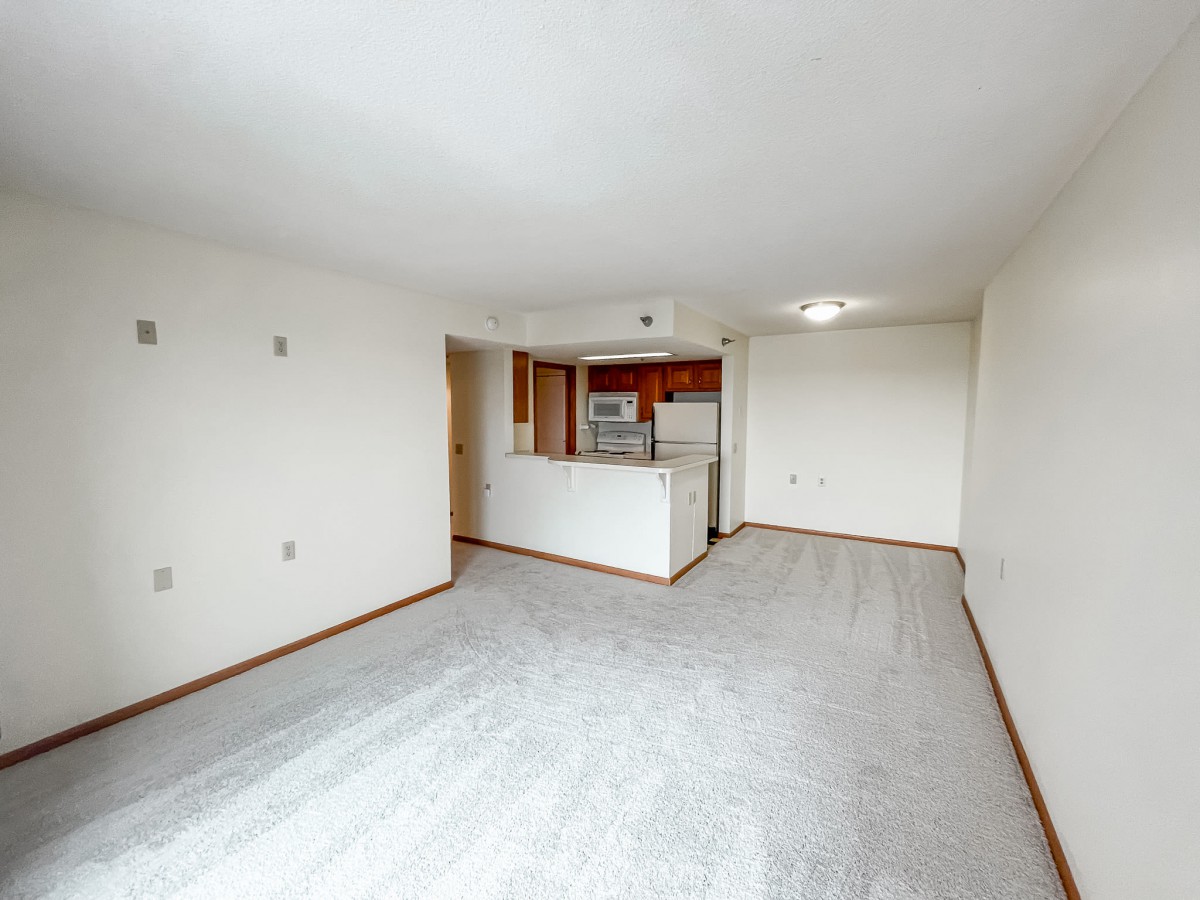 Empty apartment interior with a view of the living room and kitchen featuring an open floor plan.