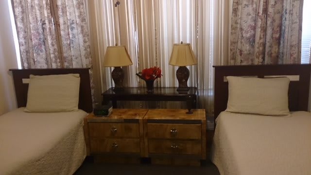 A cozy bedroom with twin beds, a shared nightstand, and decorative table lamps.