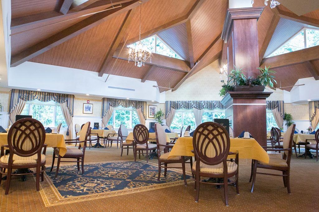 An elegant dining room with wooden ceilings, chandeliers, and beautifully arranged tables.