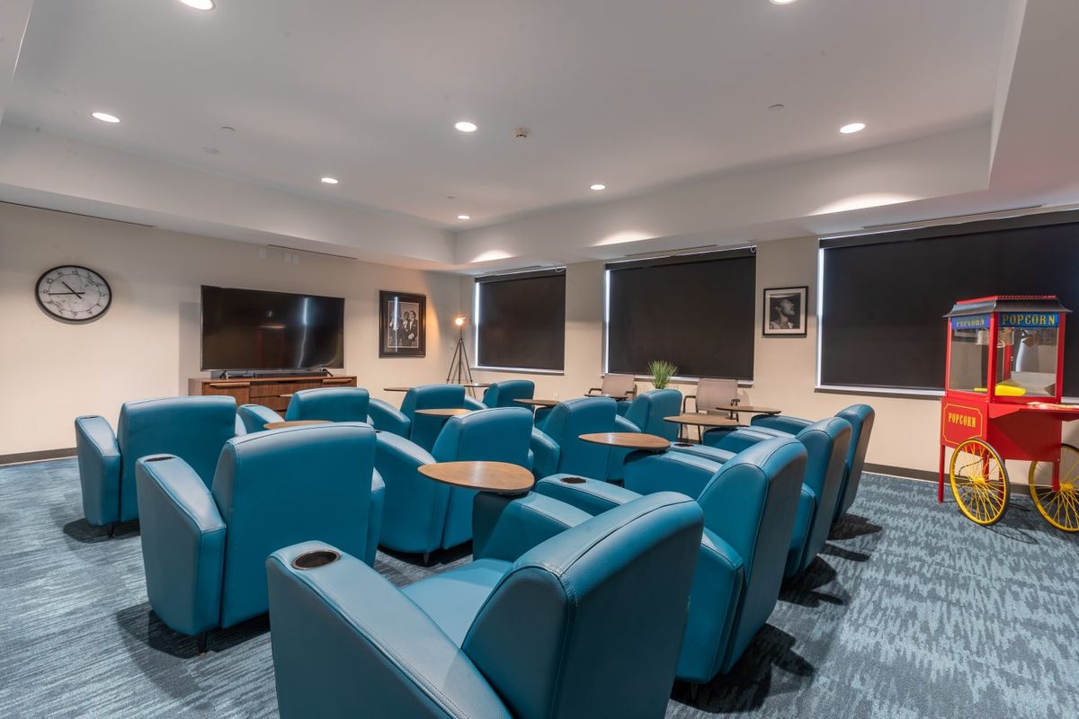 A comfortable lounge area with teal chairs arranged around a large television.