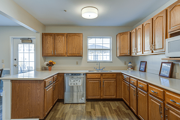 A modern kitchen with wooden cabinets and a dishwasher, featuring ample counter space and natural light from the window.