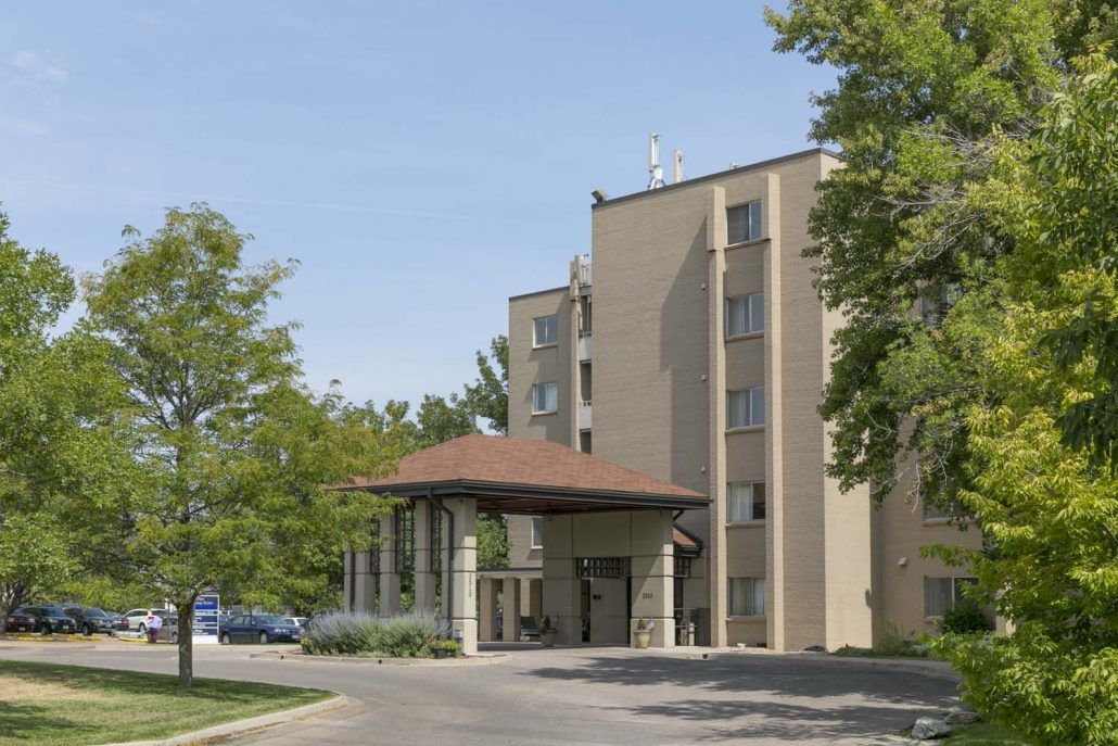 A hotel building with a driveway and surrounding trees.