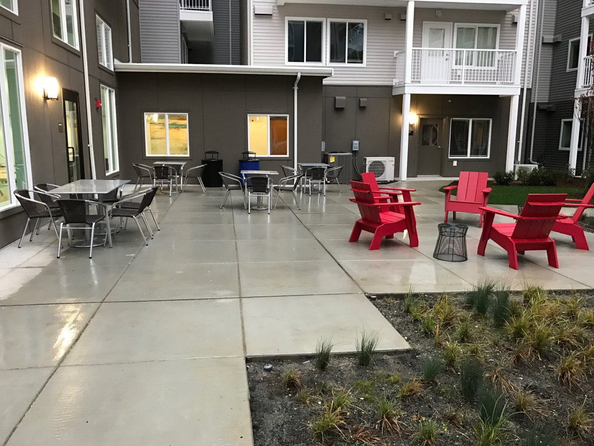 A modern outdoor patio with red chairs and tables in a residential complex.