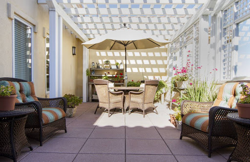 A cozy patio setup featuring comfortable seating, an umbrella for shade, and vibrant flowers.