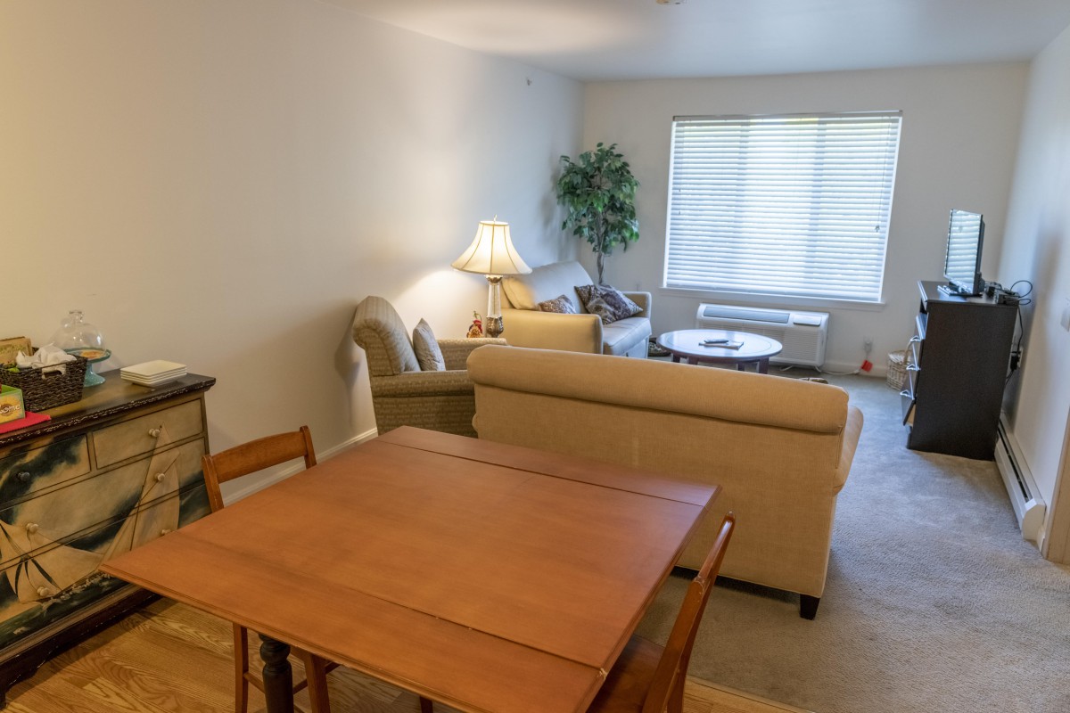 A cozy living room with a couch, table, and lamp under natural light.