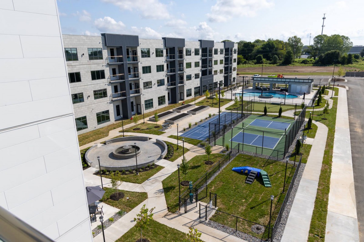 A modern apartment complex featuring tennis courts and landscaped outdoor areas.