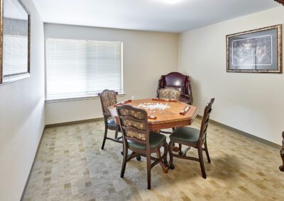 A cozy dining room with a round table and four chairs, accompanied by an armchair and large window.