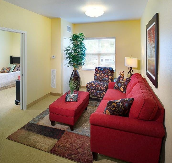A cozy living room featuring a red sofa, decorative rug, and stylish furniture.