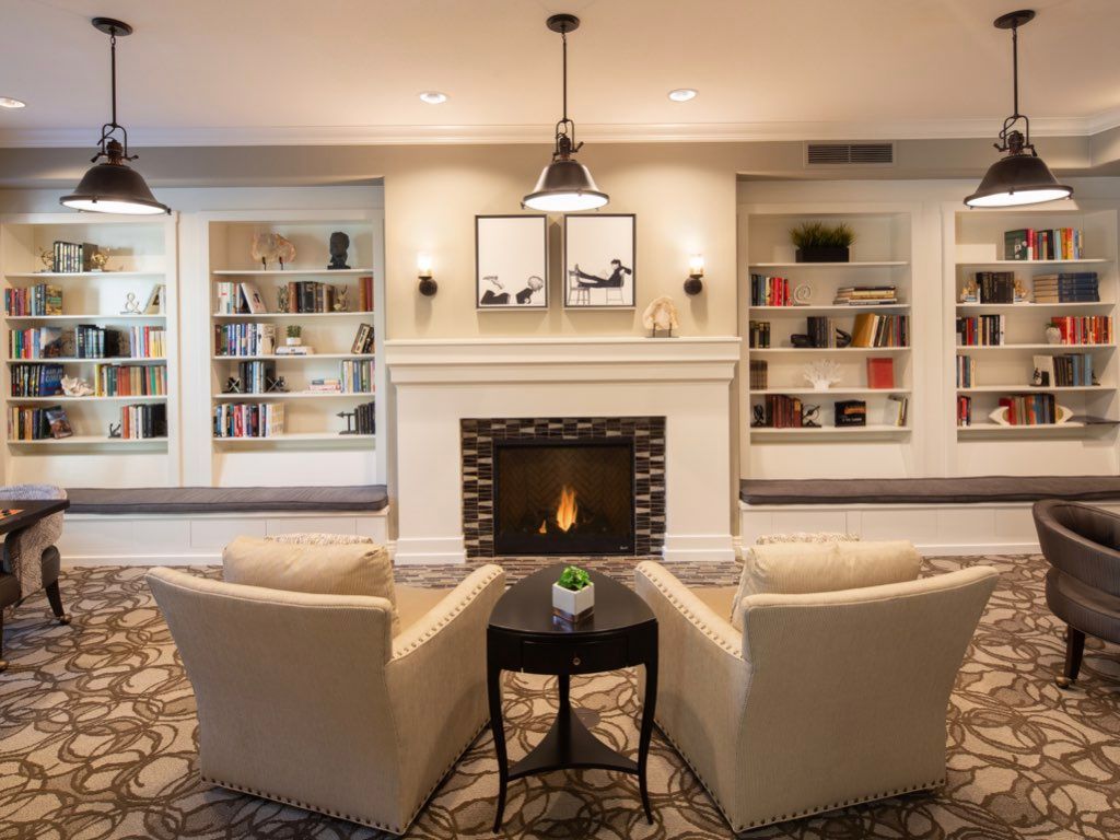 A cozy living room with a fireplace, flanked by bookshelves and two comfortable armchairs.